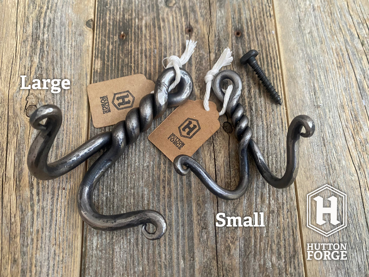 A large and small hand-forged twisted double wall hook on rustic wood, labeled Large and Small. Hutton Forge.
