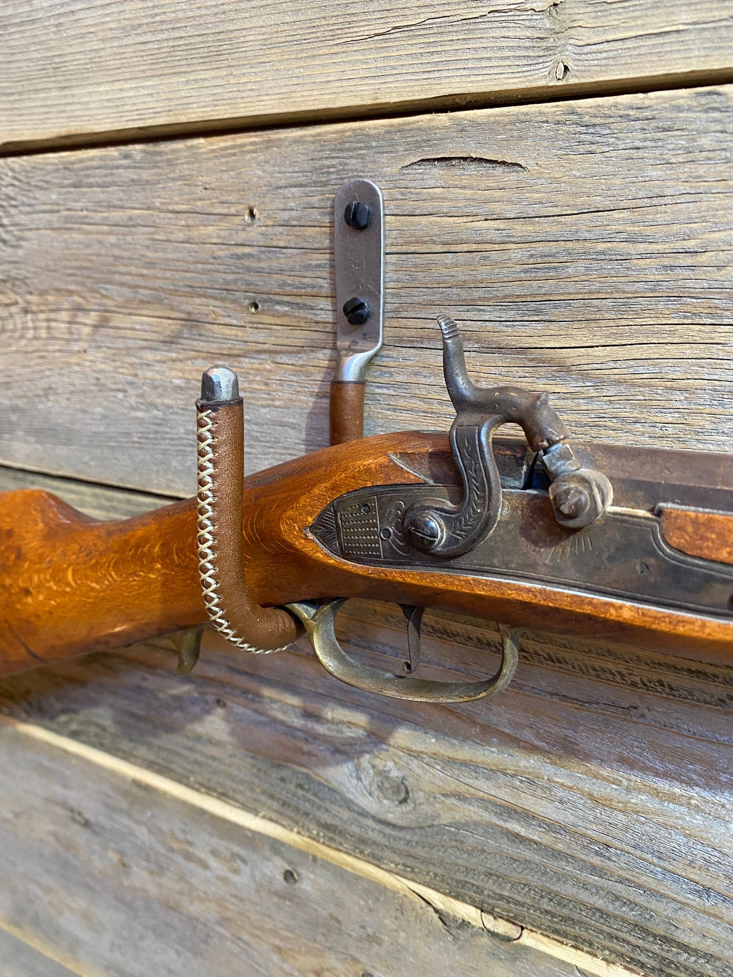 Close up shot of the leather wrapped gun hook displaying an antique rifle.