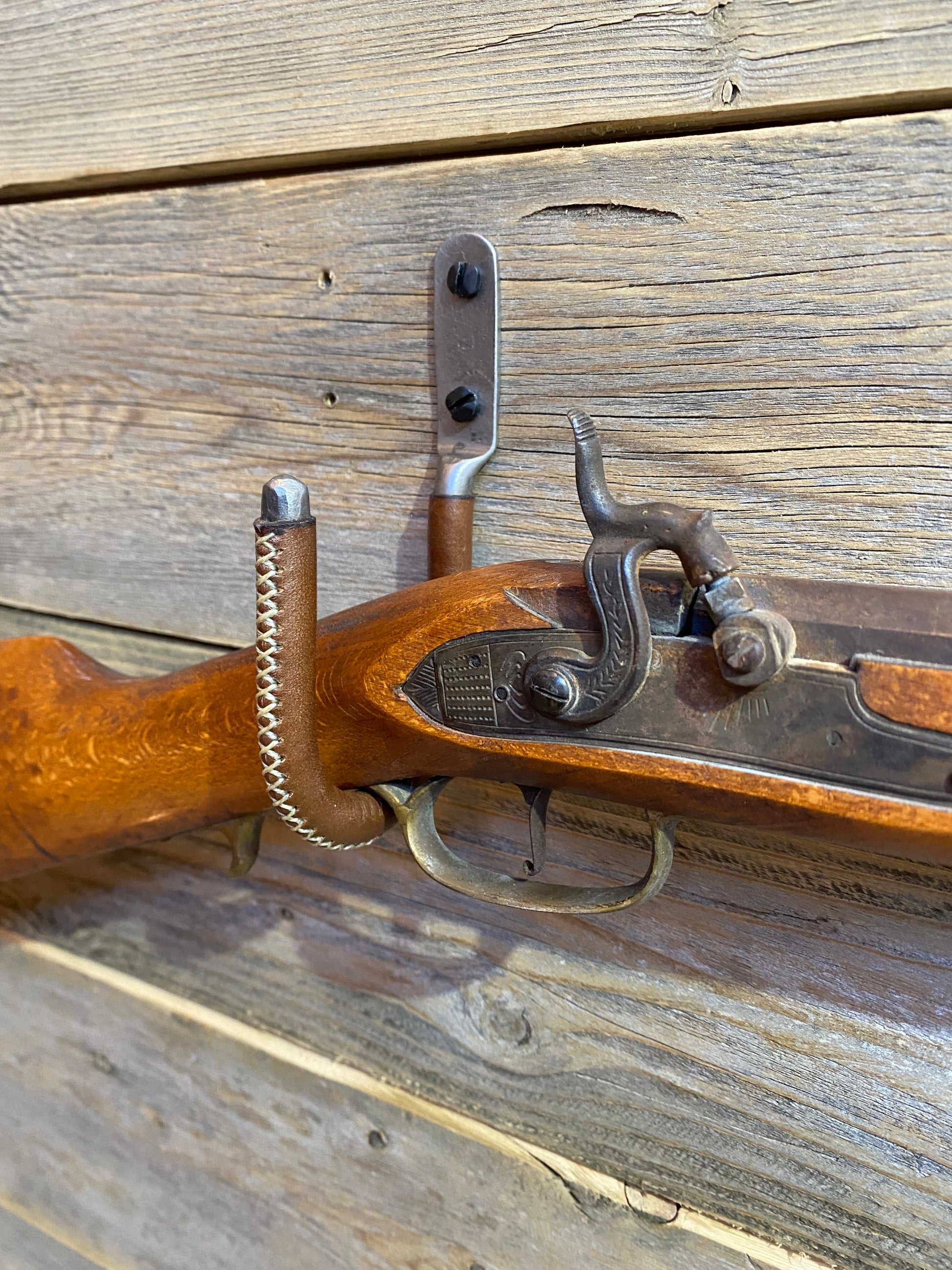 Close up shot of the leather wrapped gun hook displaying an antique rifle.