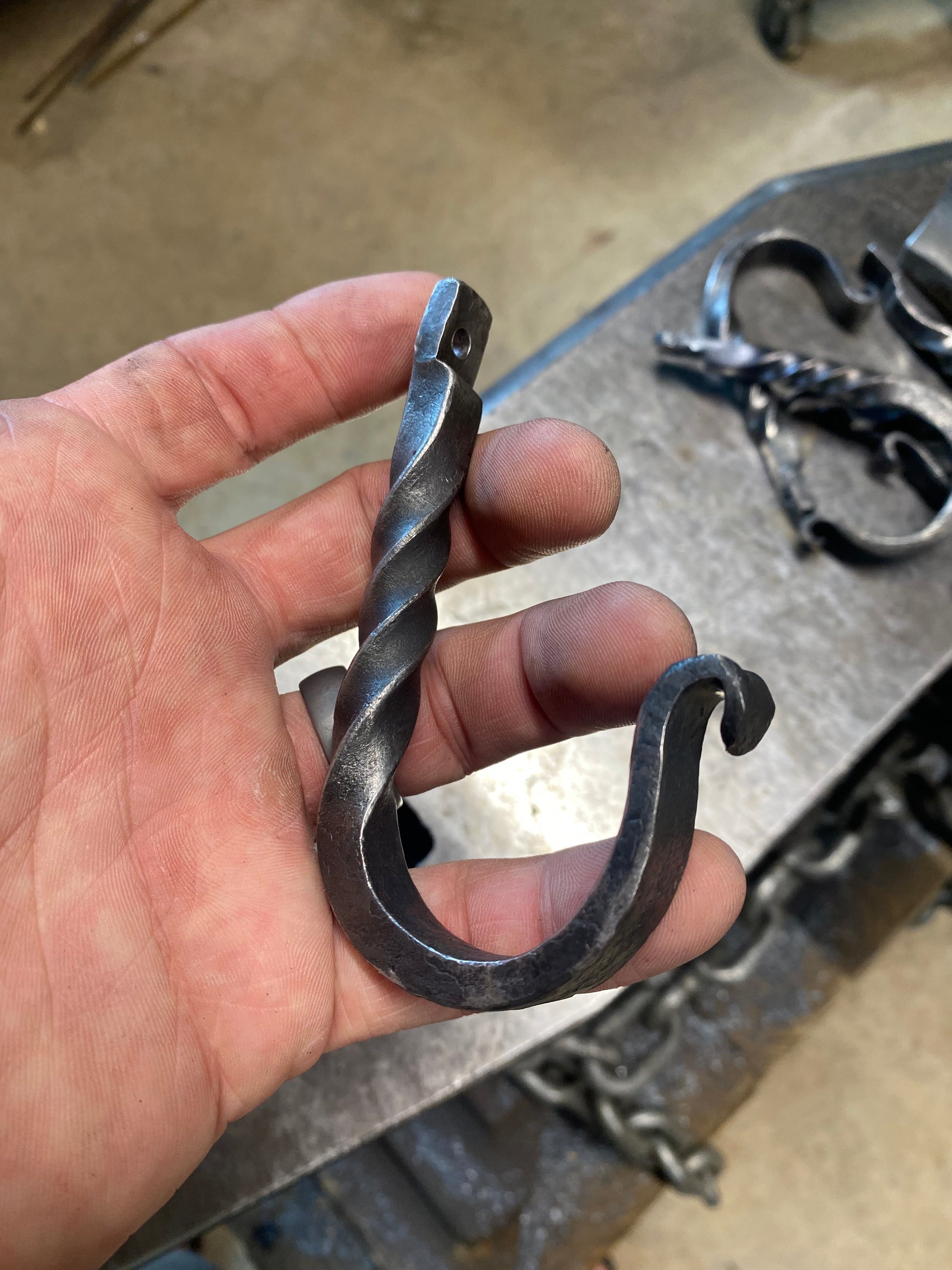 Hand-forged twisted steel J-hook in blackened finish, blacksmith-made with a decorative twist. Hutton Forge.

