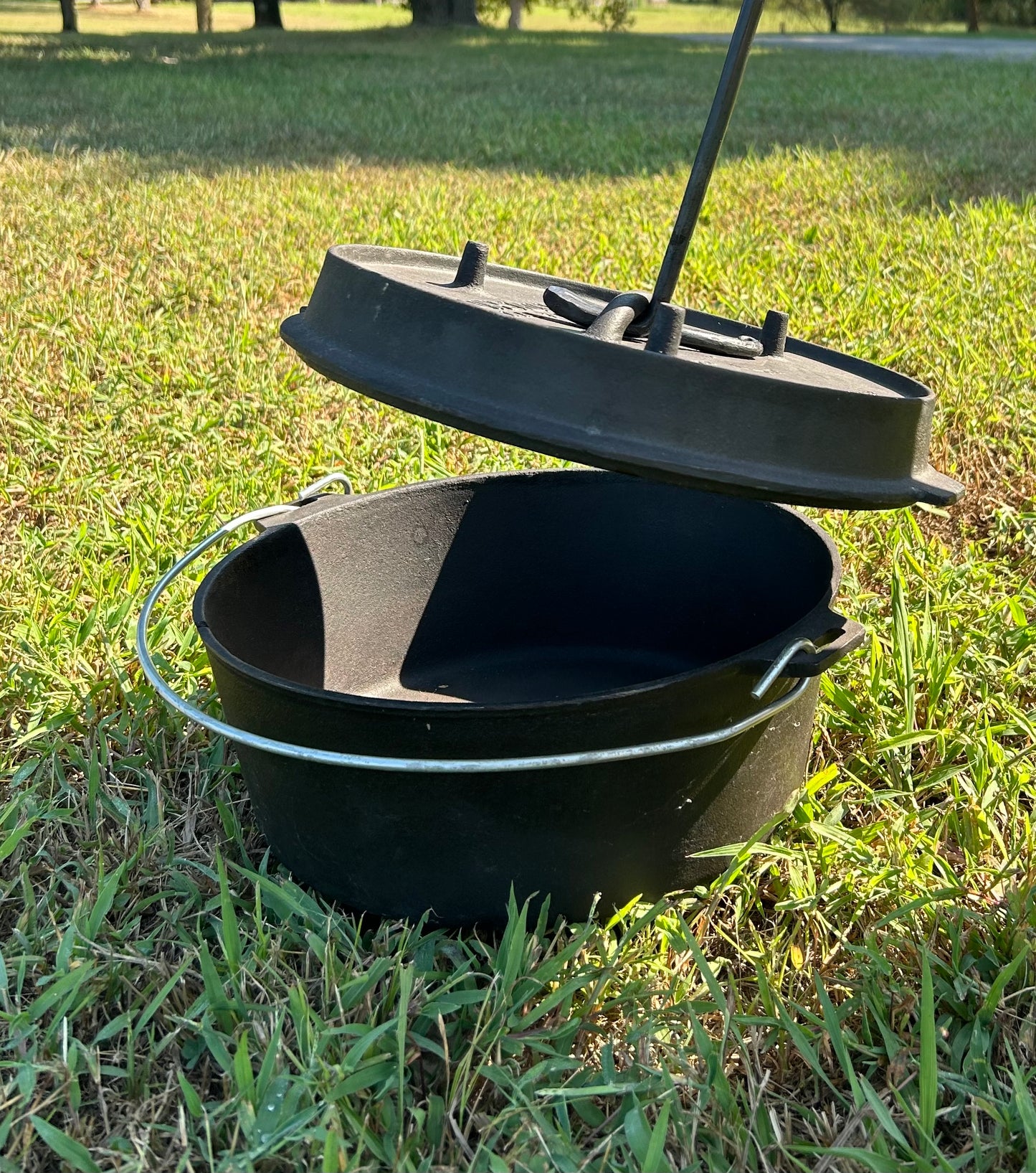 A hand-forged twisted steel Dutch oven lid lifter over a Dutch Oven. Made by Hutton Forge.