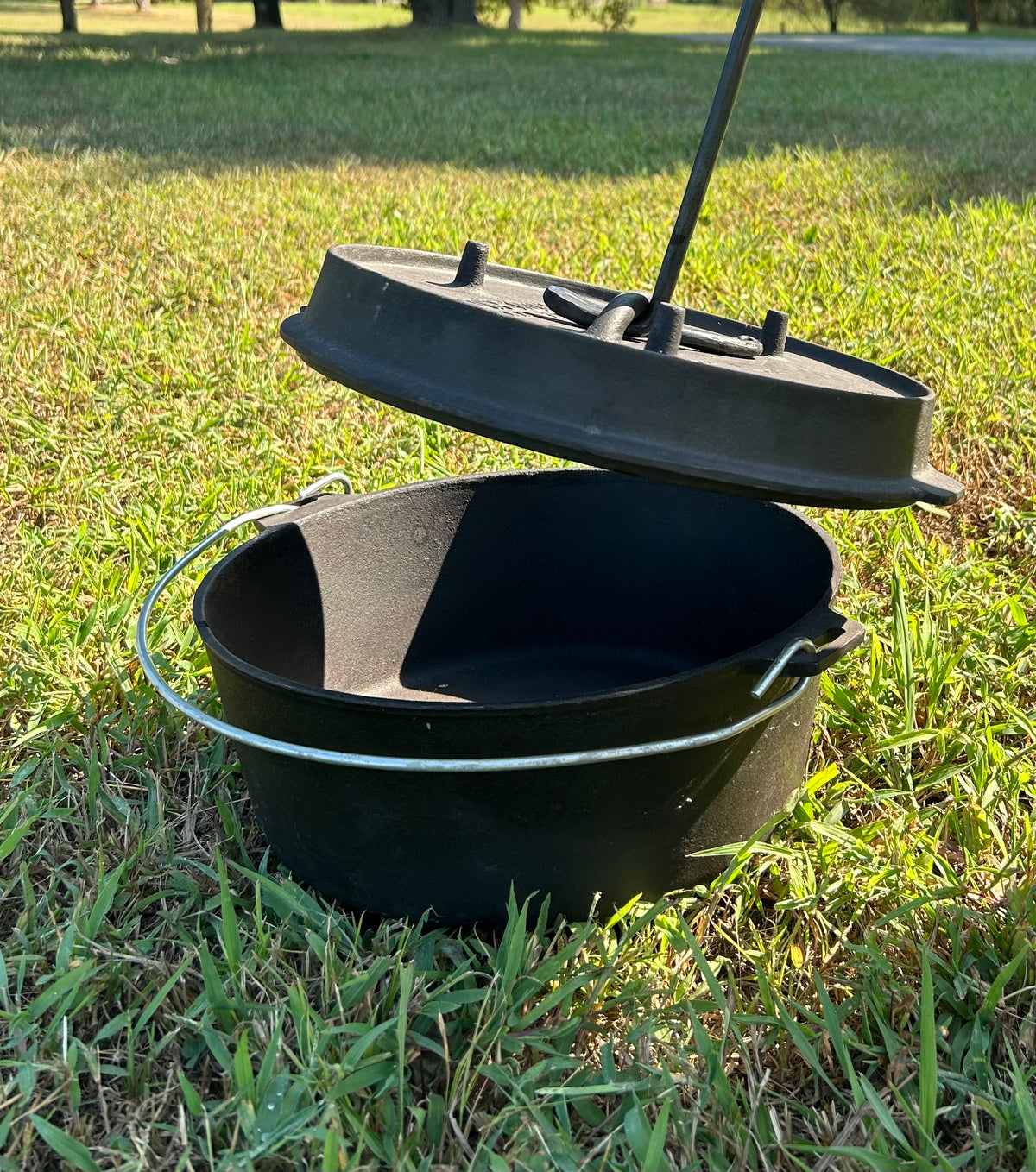 A hand-forged twisted steel Dutch oven lid lifter over a Dutch Oven. Made by Hutton Forge.
