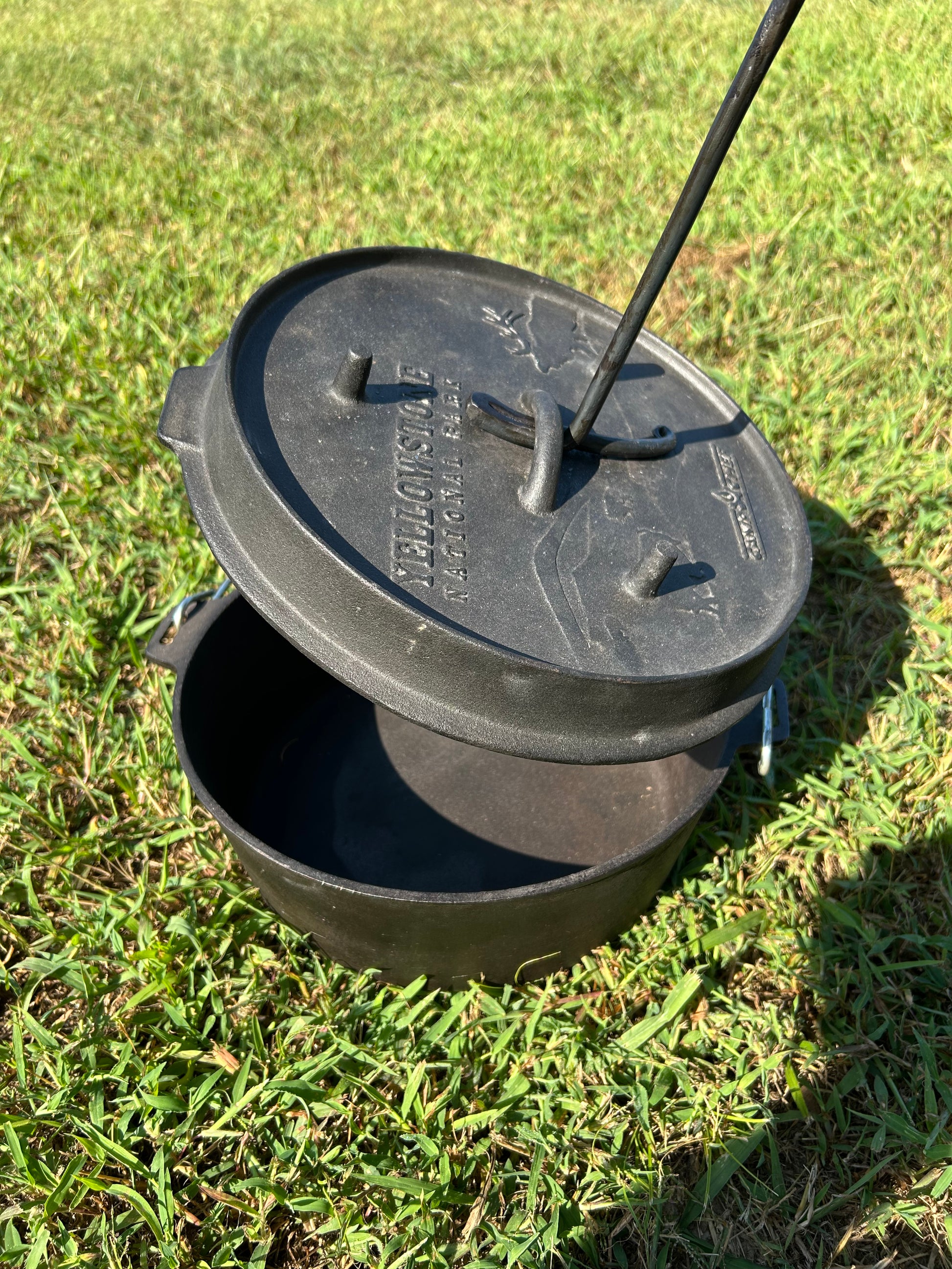 Blacksmith-made Dutch oven lid lifter with a twisted steel shaft, hooked end, and curved handle. Hutton Forge.