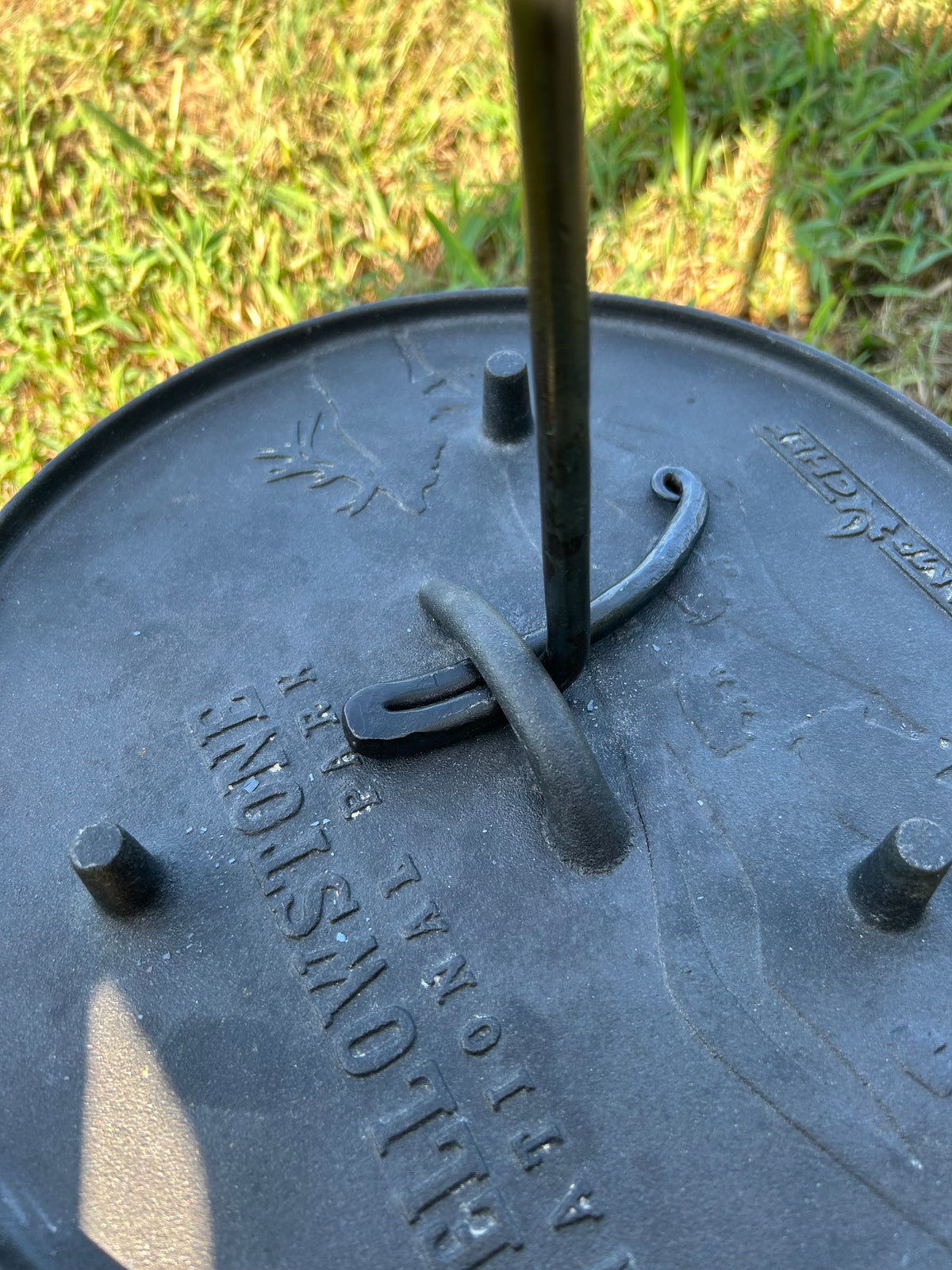 A hand-forged twisted steel Dutch oven lid lifter over a Dutch Oven. Made by Hutton Forge.