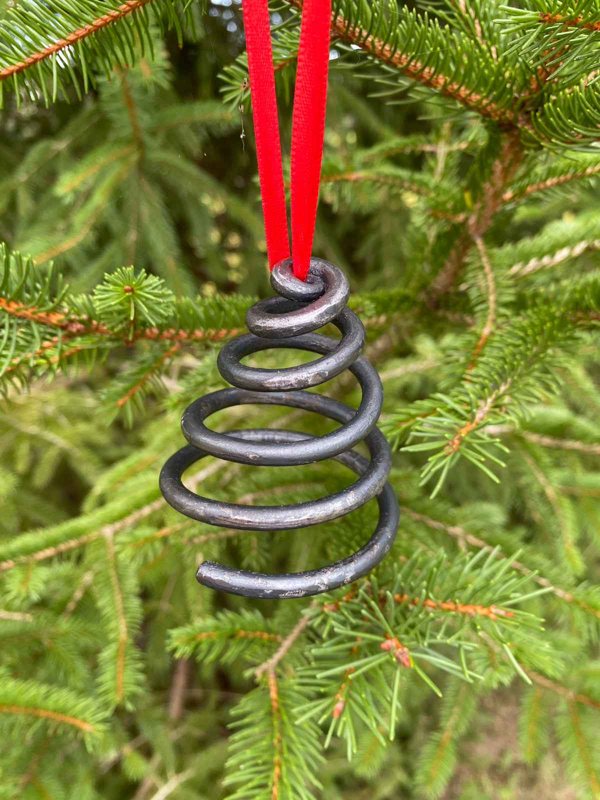 Unique blacksmith spiral Christmas tree ornament hanging on a Christmas Tree. Hutton Forge