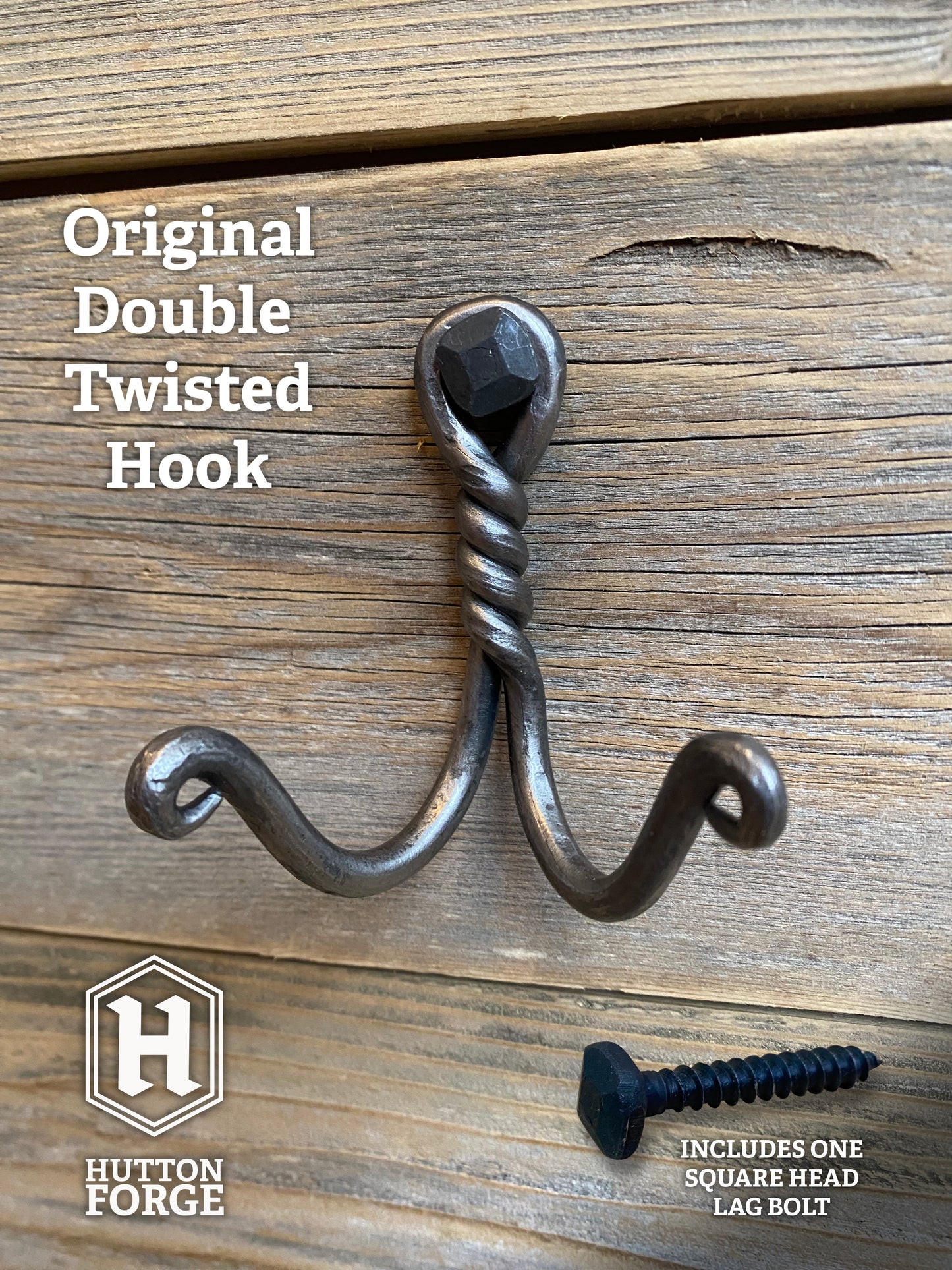Hand-forged twisted double wall hook in blackened steel, mounted with a hexagonal bolt on rustic wooden boards. Hutton Forge.

