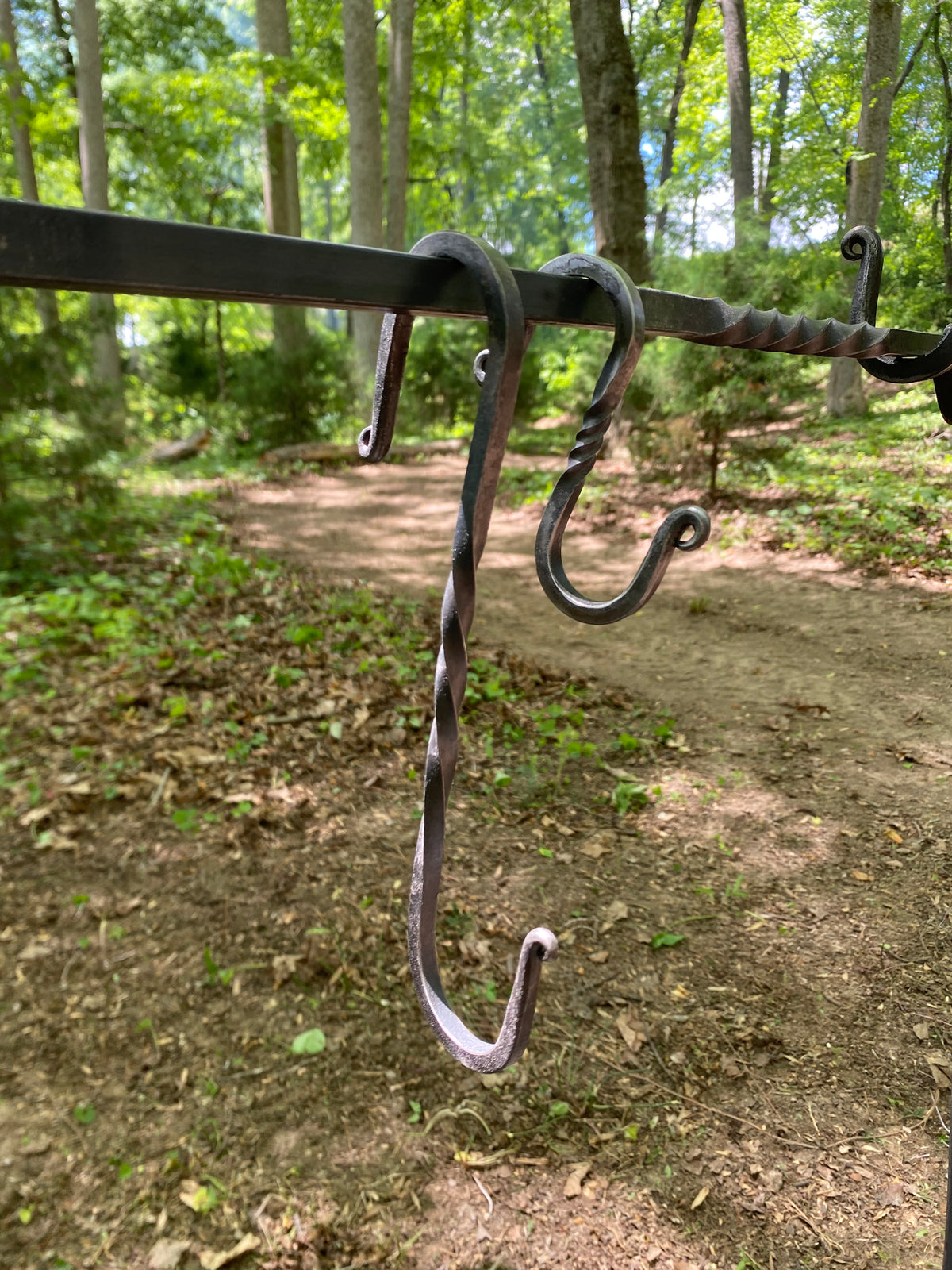  A handcrafted, dark metal campfire cooking set with 2 S-hooks, small and large. The hooks can be used to hang a pot over a fire.