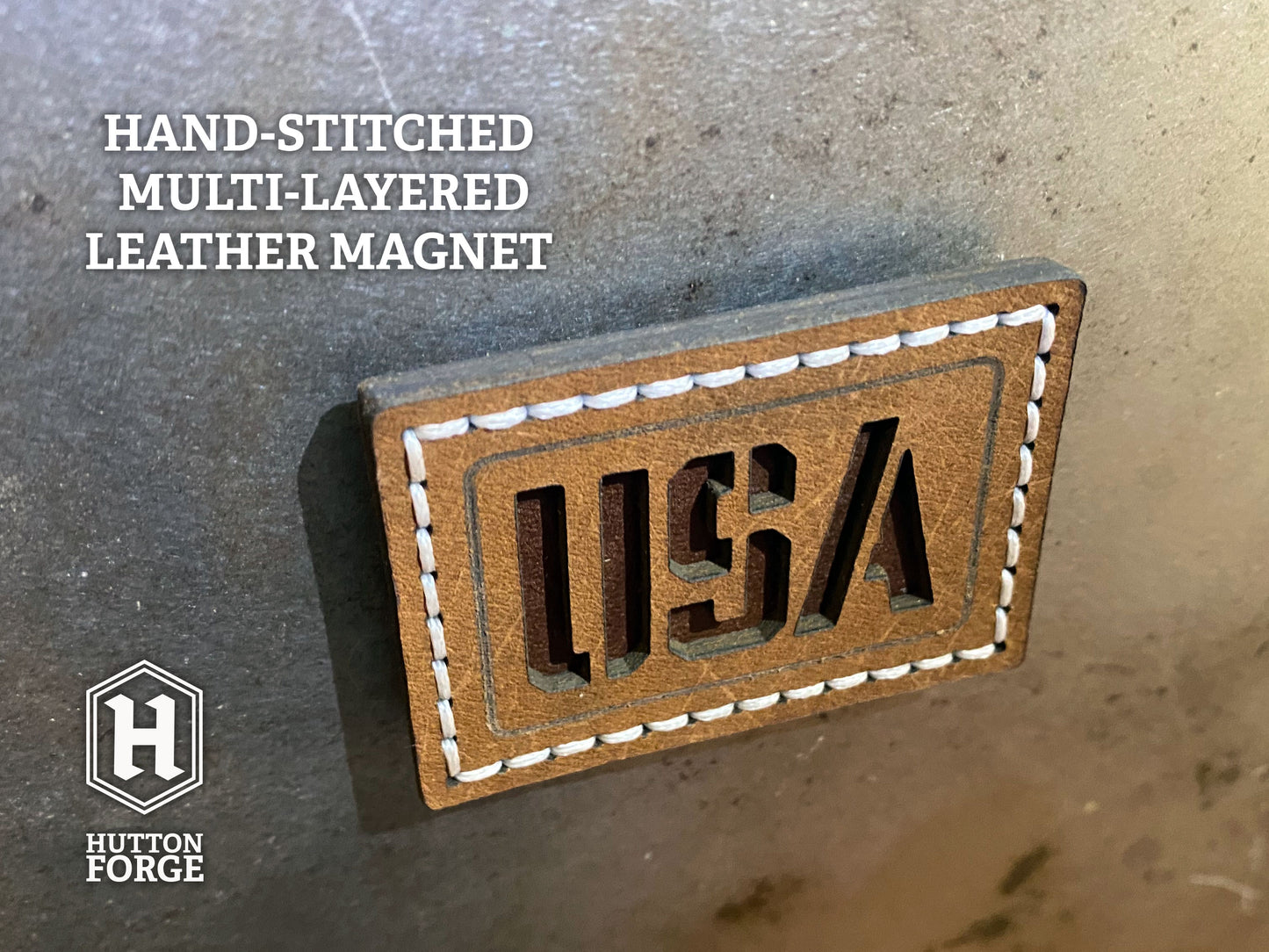 Hand-stitched brown leather magnet with cut-out “USA” lettering, white stitching on a rectangle design. Hutton Forge.